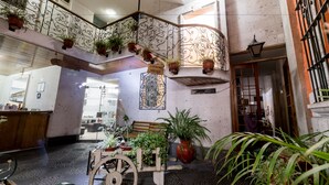 A spacious interior with a wooden bench, a cart with plants, and a sign for laundry service. - Hostal Villa Sillar (Arequipa)