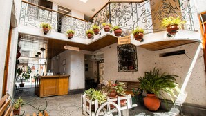A multi-level interior with potted plants, a laundry service sign, and a wooden bench. - Hostal Villa Sillar (Arequipa)