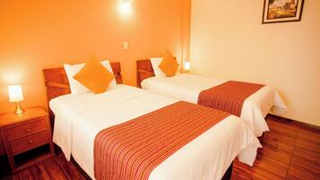 A hotel room with two beds, wooden headboards, a nightstand with a lamp, and a framed picture on the wall.