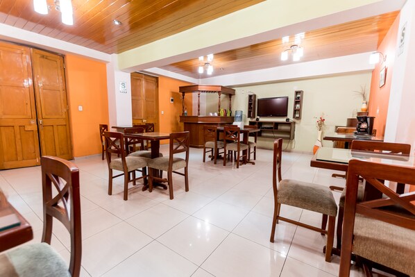 Un comedor con mesas y sillas de madera, una barra y un televisor.
