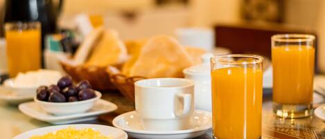 A breakfast table with plates of food, glasses of orange juice, and a coffee pot.