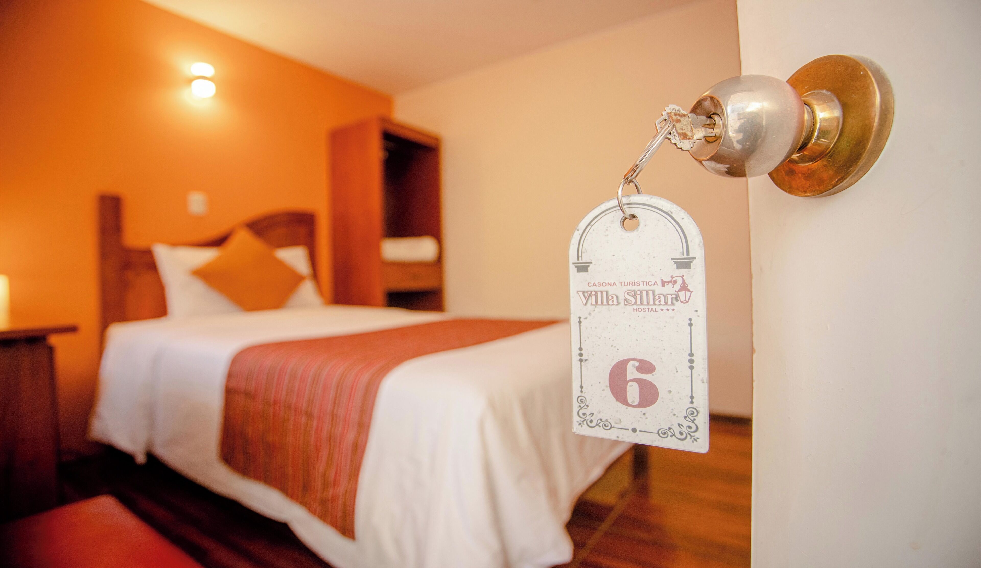 A hotel room with a bed, a nightstand, and a door with a keycard lock.