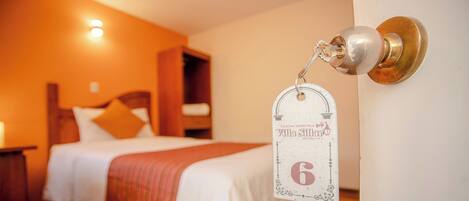 A hotel room with a bed, a nightstand, and a door with a keycard lock.