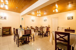 Comedor con techo y paredes de madera, mesas con manteles blancos y sillas.