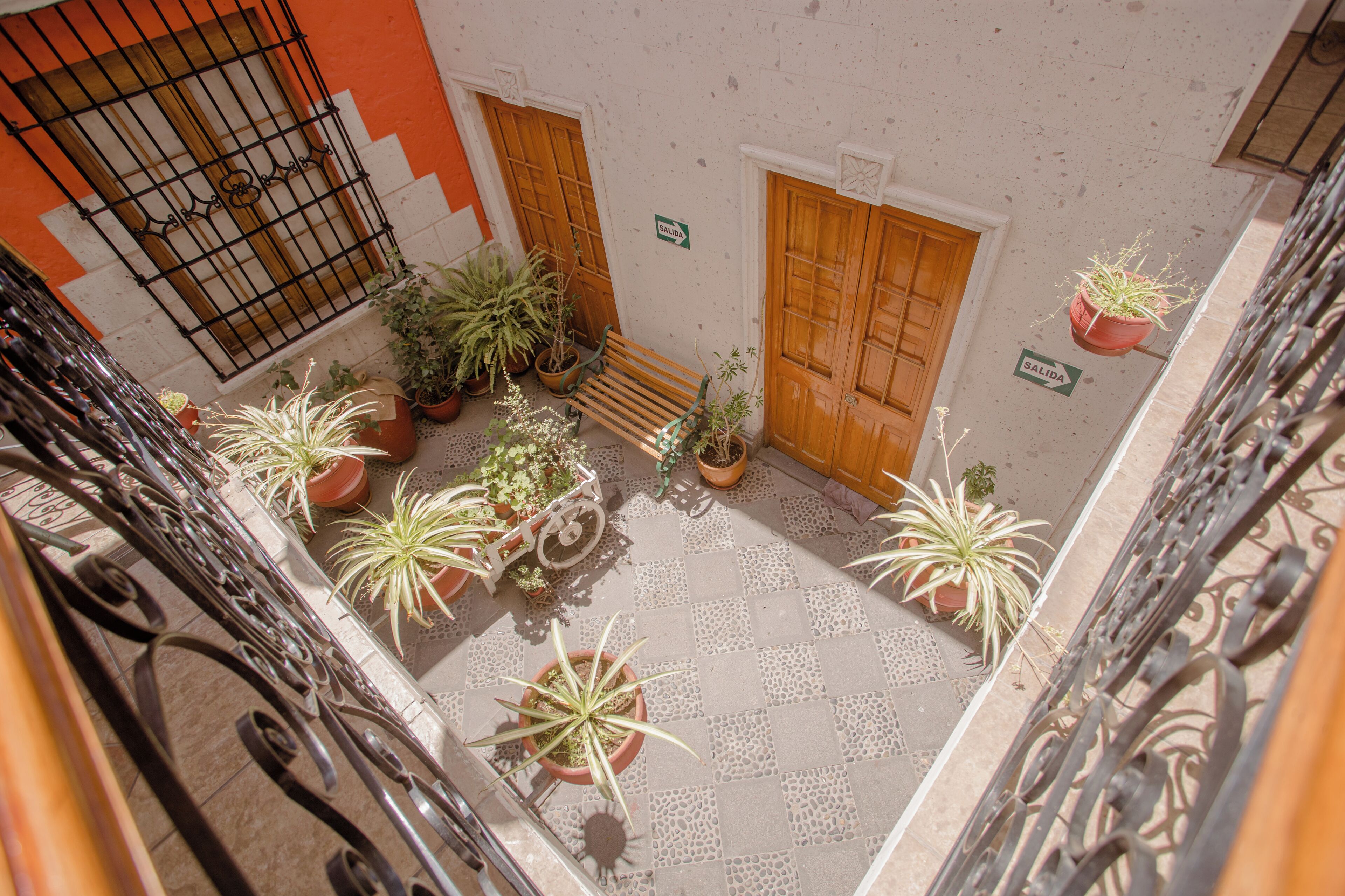 Un patio con plantas en macetas, un banco de madera y una barandilla de metal.