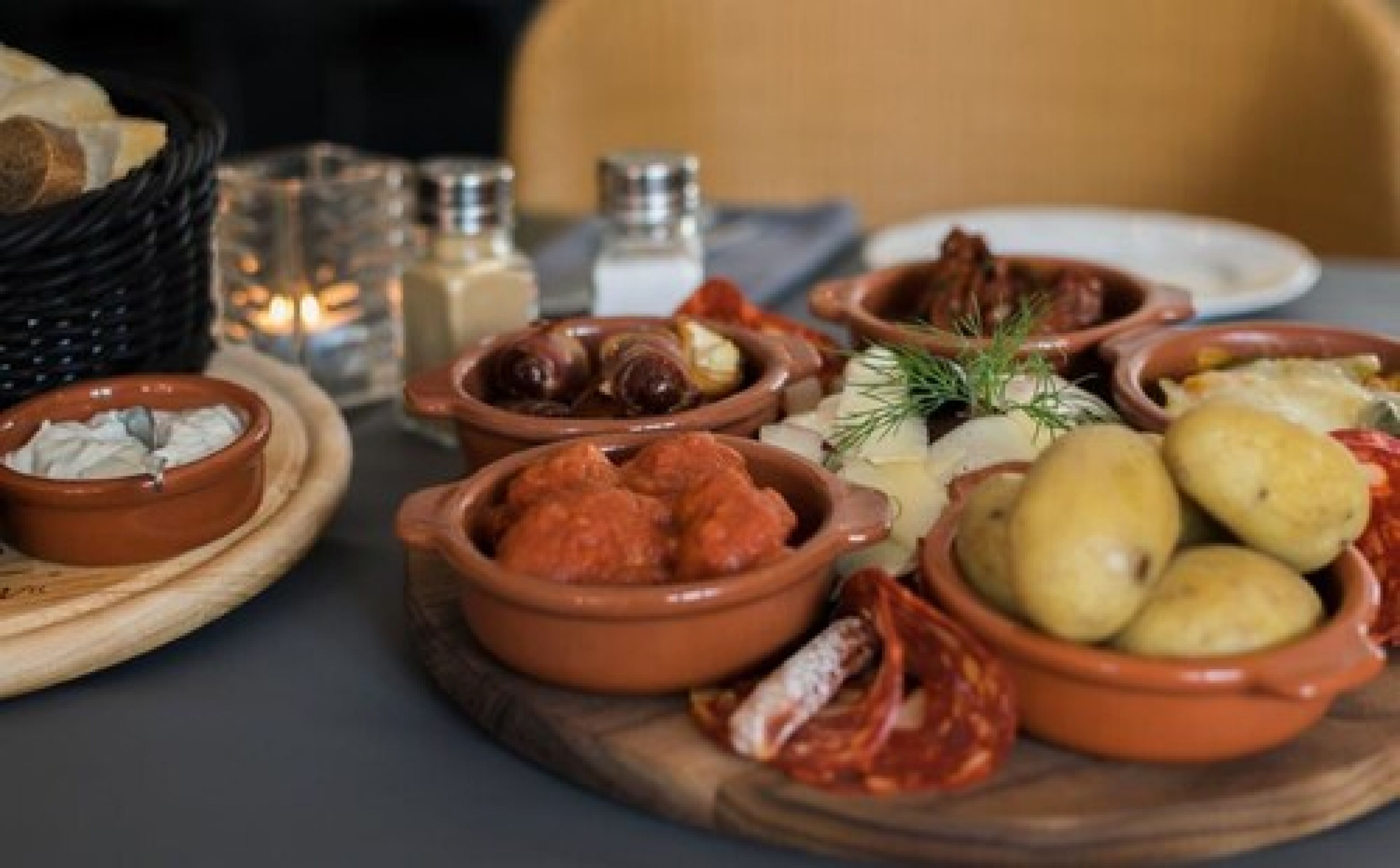 Een tafel met diverse etenswaren, zoals olijven, kaas en brood.