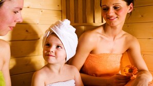 Three people in a wooden cabin with a sauna.