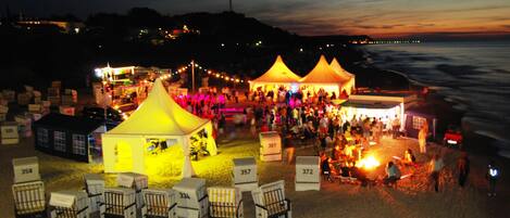 Un evento a la orilla de la playa con carpas y sillas, algunas numeradas.