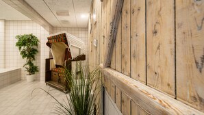 A hallway with a wooden wall, a potted plant, and a wicker chair.