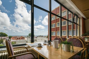 Un comedor con mesa, sillas y vistas a edificios y al mar.