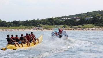 Una balsa amarilla con pasajeros siendo remolcada por un bote a motor sobre el agua.