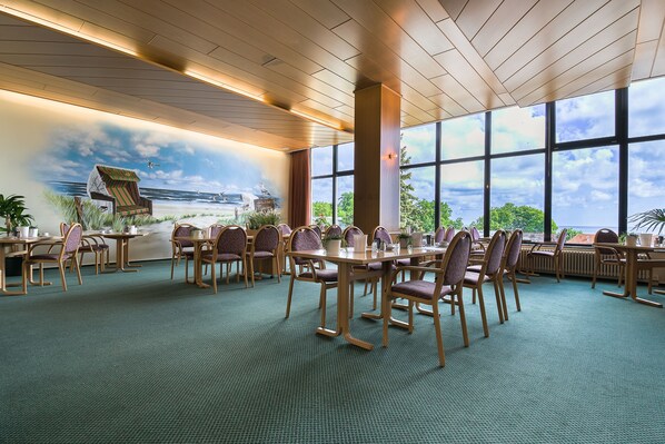 A conference room with a large table and chairs, a mural of a beach scene, and large windows offering a view of the outdoors.
