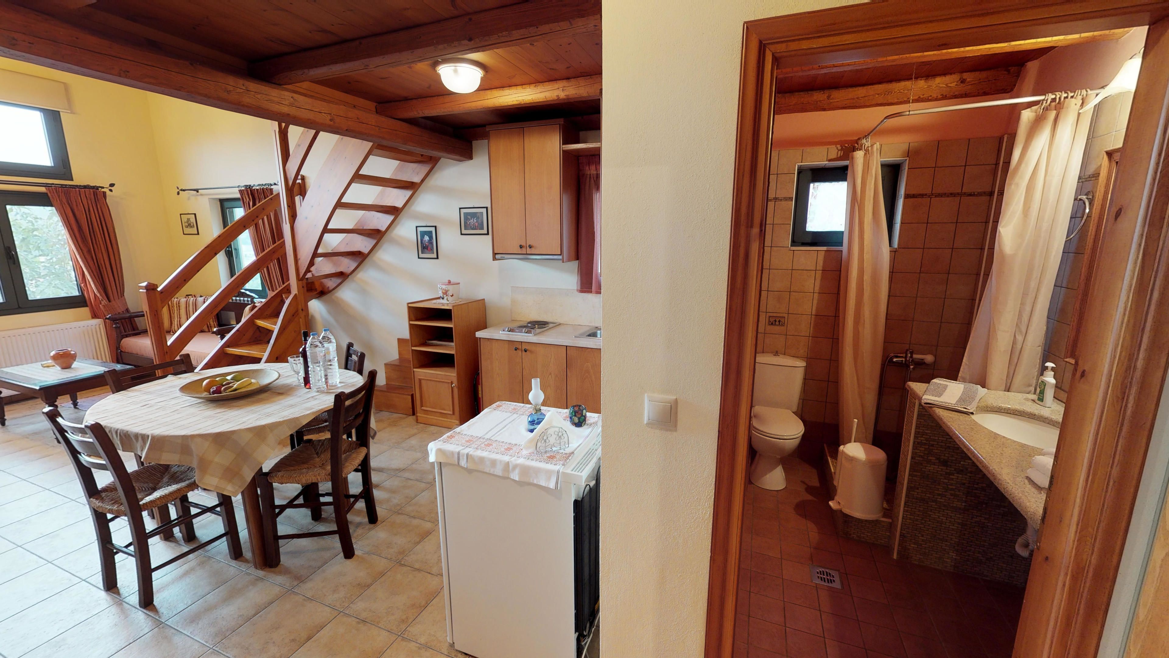 Une cuisine compacte avec des meubles en bois, une table à manger avec des chaises, une cuisinière encastrée et un petit réfrigérateur.