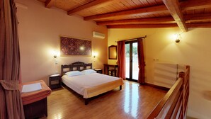 A bedroom with a wooden ceiling, a bed, a nightstand, a desk, a chair, a radiator, and a window with curtains. - Nana Apartments (Faistos)