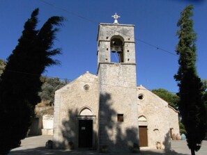 A church with a bell tower, arched windows, and a cross at the top. - Nana Apartments (Faistos)
