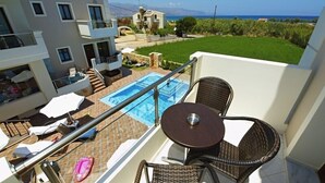 Un balcon avec une piscine, des fauteuils en osier et une table.