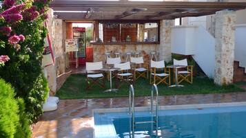 Un espace piscine extérieur doté d’un bar, de sièges et d’un mur en pierre.