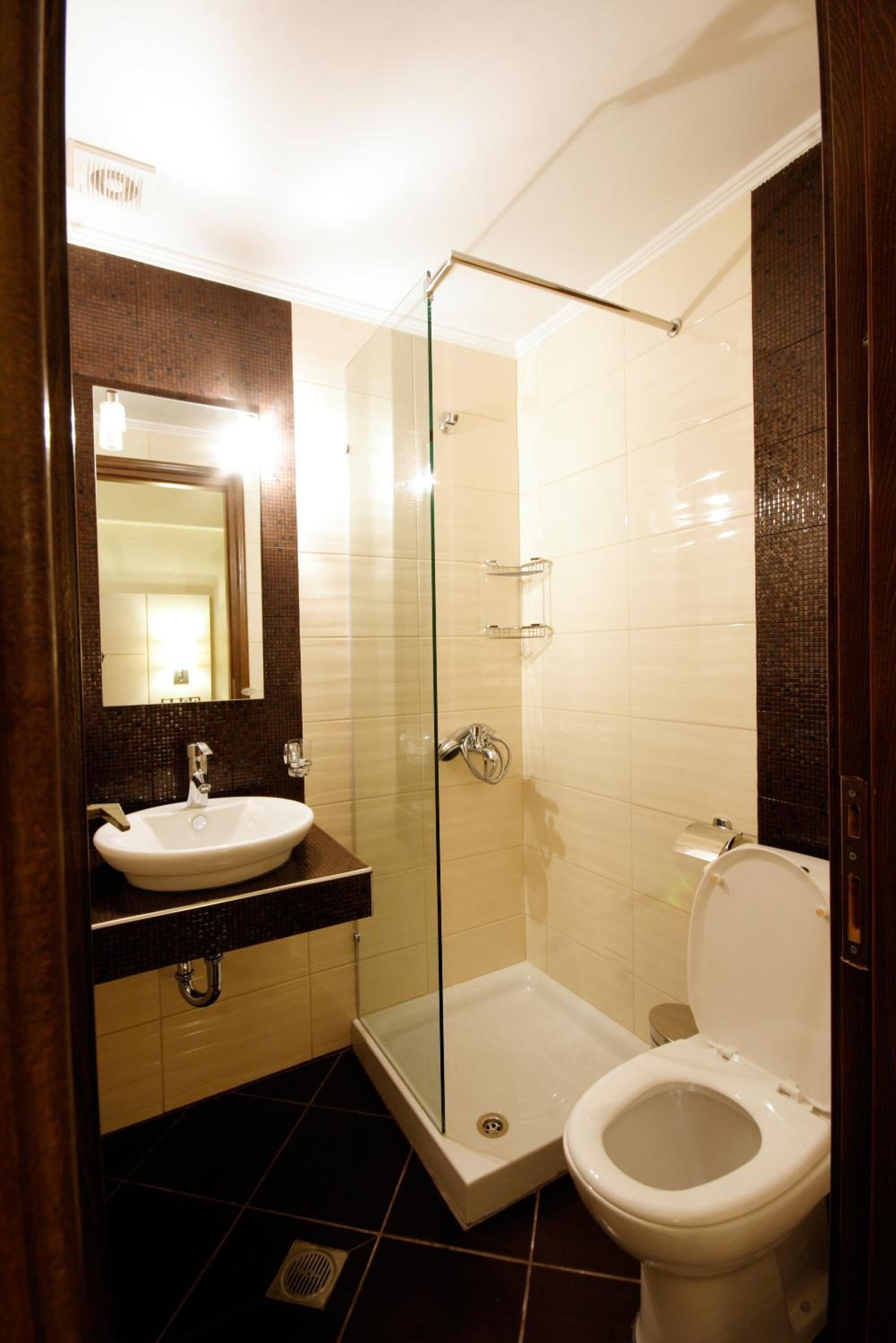 Une salle de bain avec une douche à parois de verre, un lavabo avec un miroir et des toilettes.