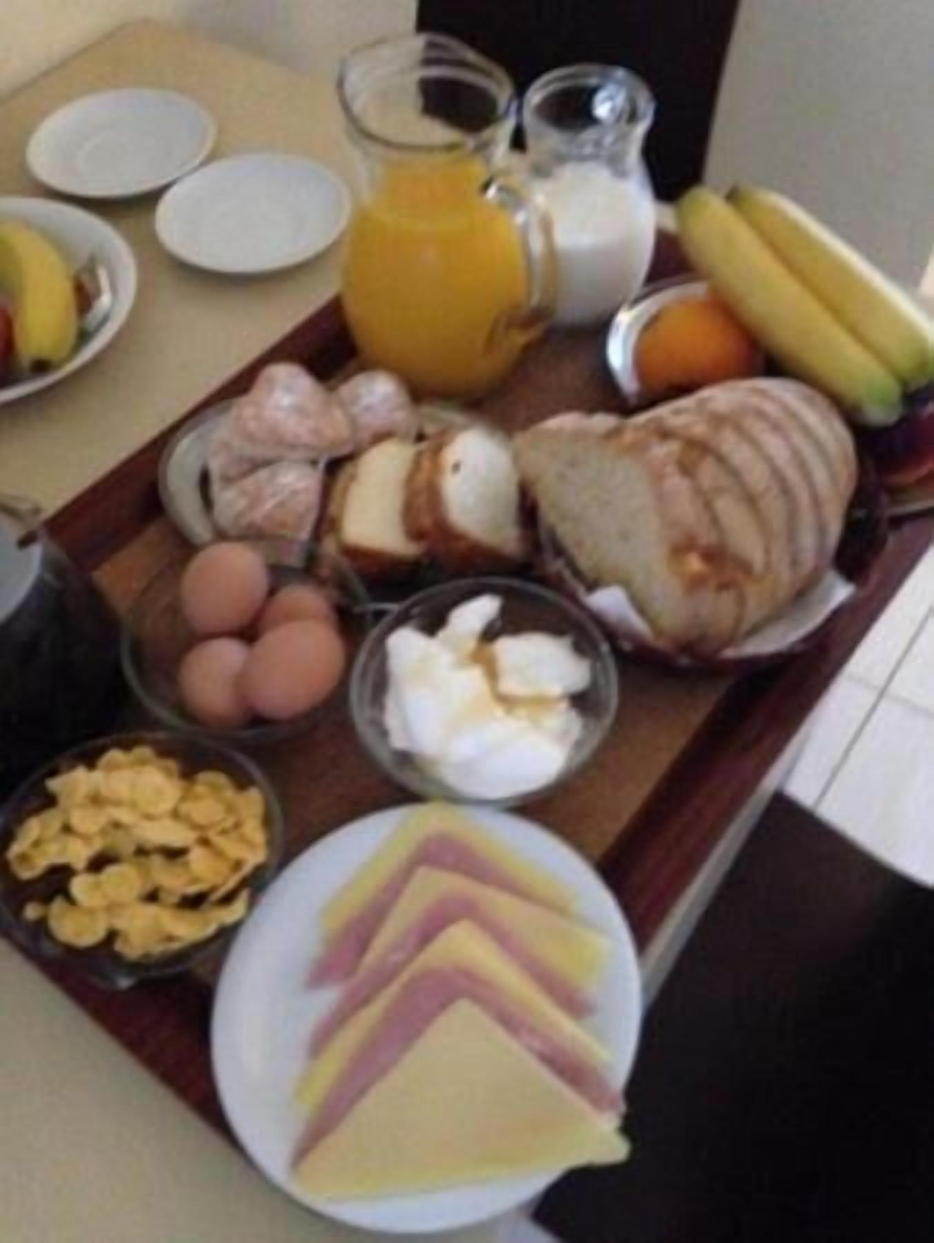 A breakfast tray with eggs, cereal, cheese, bread, and fruit.