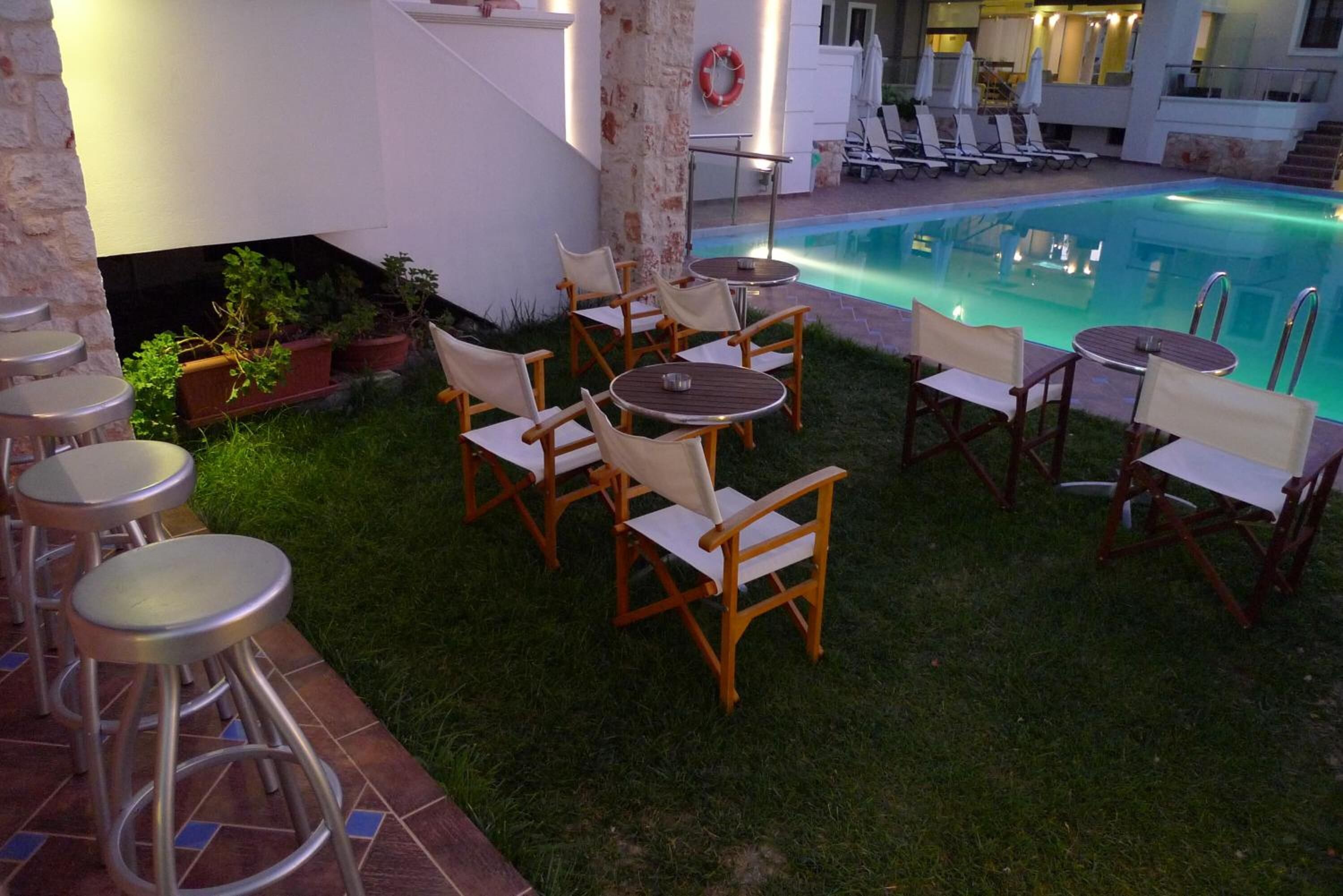A poolside area with multiple chairs and tables, a bar area with stools, and a lifebuoy on the wall.