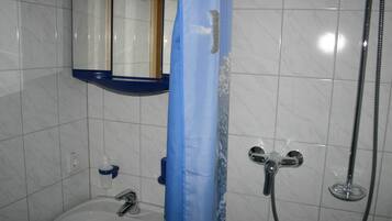 A bathroom with a sink, mirror, shower, and blue shower curtain.