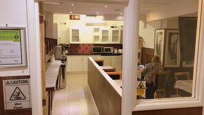 A hotel kitchen with a wet floor sign, a caution sign, and a hygiene rating sign. - Plaza London Hotel (London)