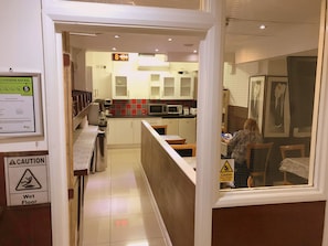 Een hotelkeuken met een bord dat aangeeft dat de vloer nat is, een waarschuwingsbord en een bord met een hygiënescore.
