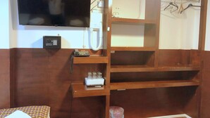A room with a television mounted on the wall, a telephone, and a shelf with a small appliance. - Plaza London Hotel (London)