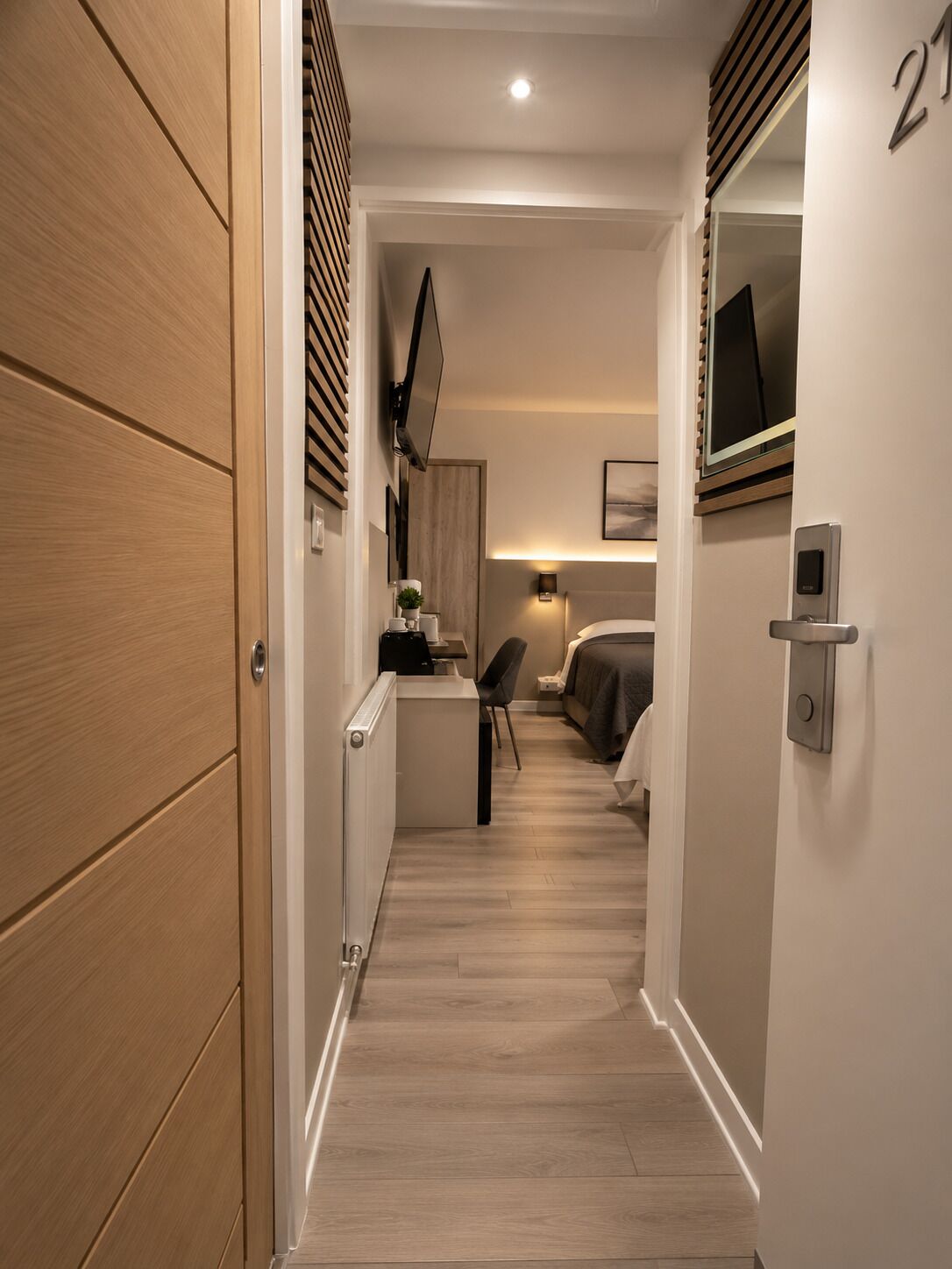 Un couloir étroit avec un lit, une table de chevet et un bureau avec une chaise.