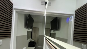 A narrow hallway with a wooden floor, white walls, and a mirrored wall on one side. - Plaza London Hotel (London)