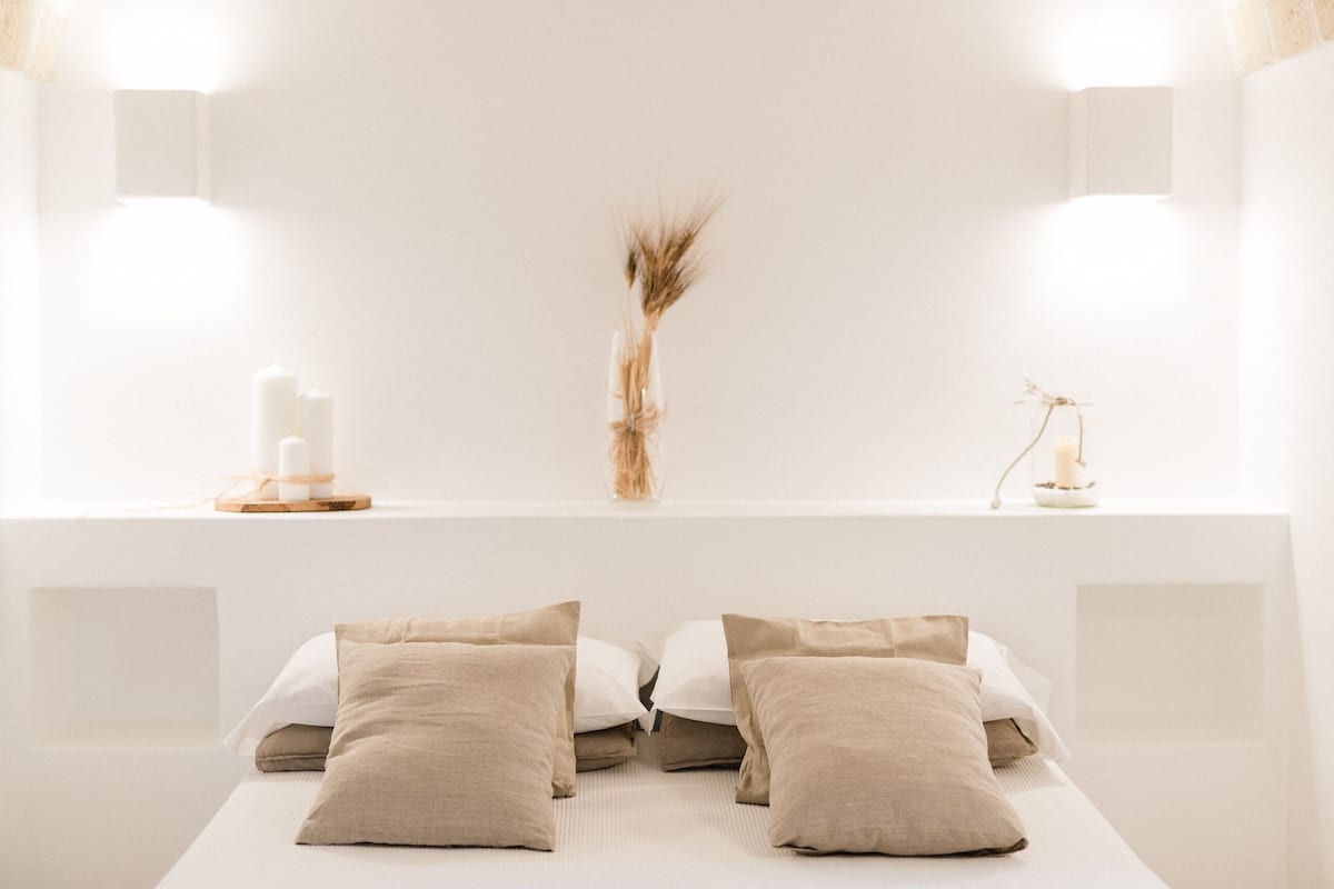 A minimalist room with a bed, two bedside tables, and a wall-mounted light fixture.