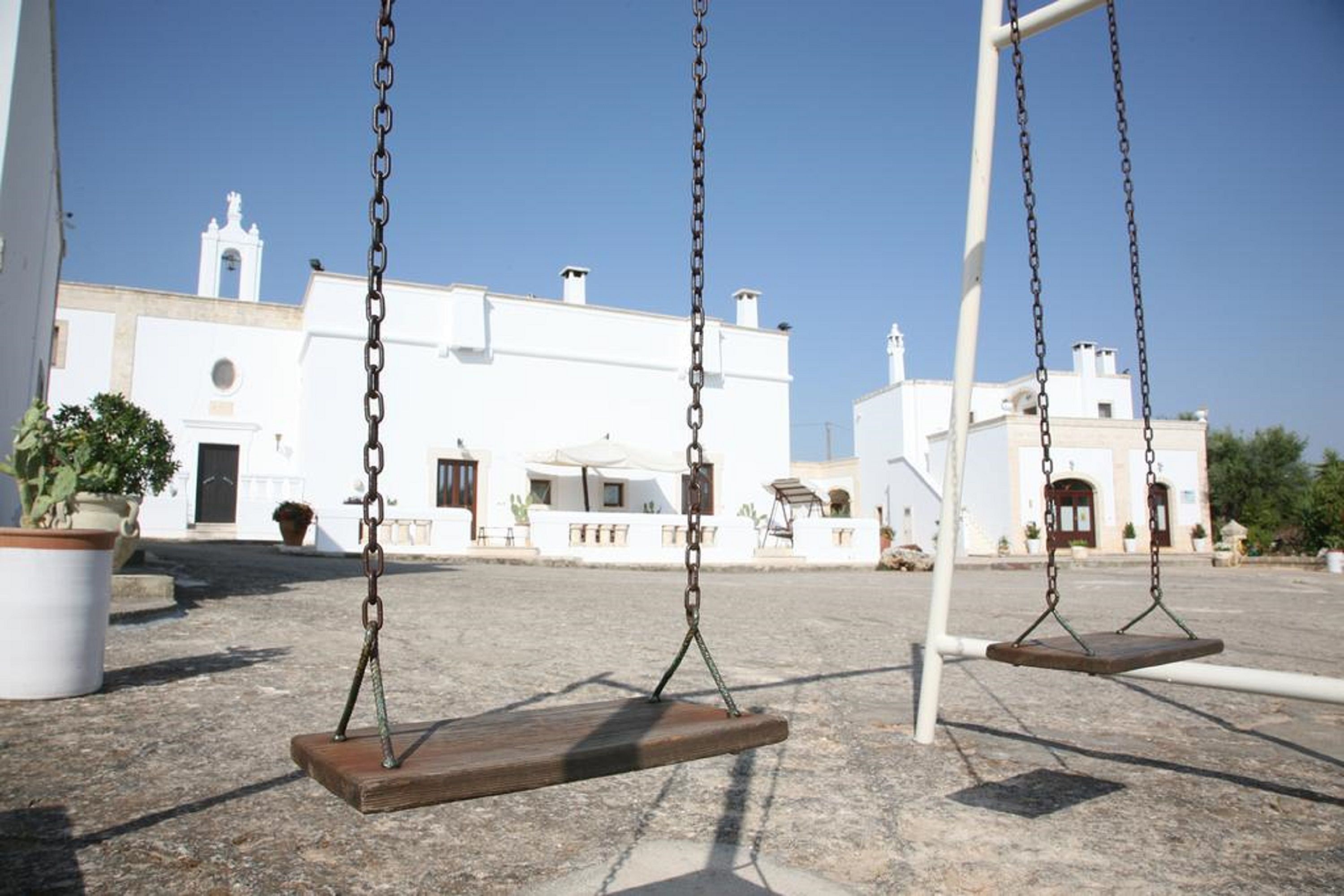 A set of swings in an outdoor area with a white building in the background.