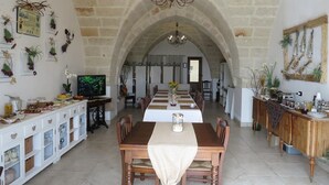 Une vaste salle à manger dotée d’un haut plafond en pierre, d’un lustre et d’une longue table dressée pour le repas.