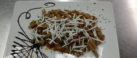 A plate of pasta with grated cheese and a decorative chocolate drizzle.