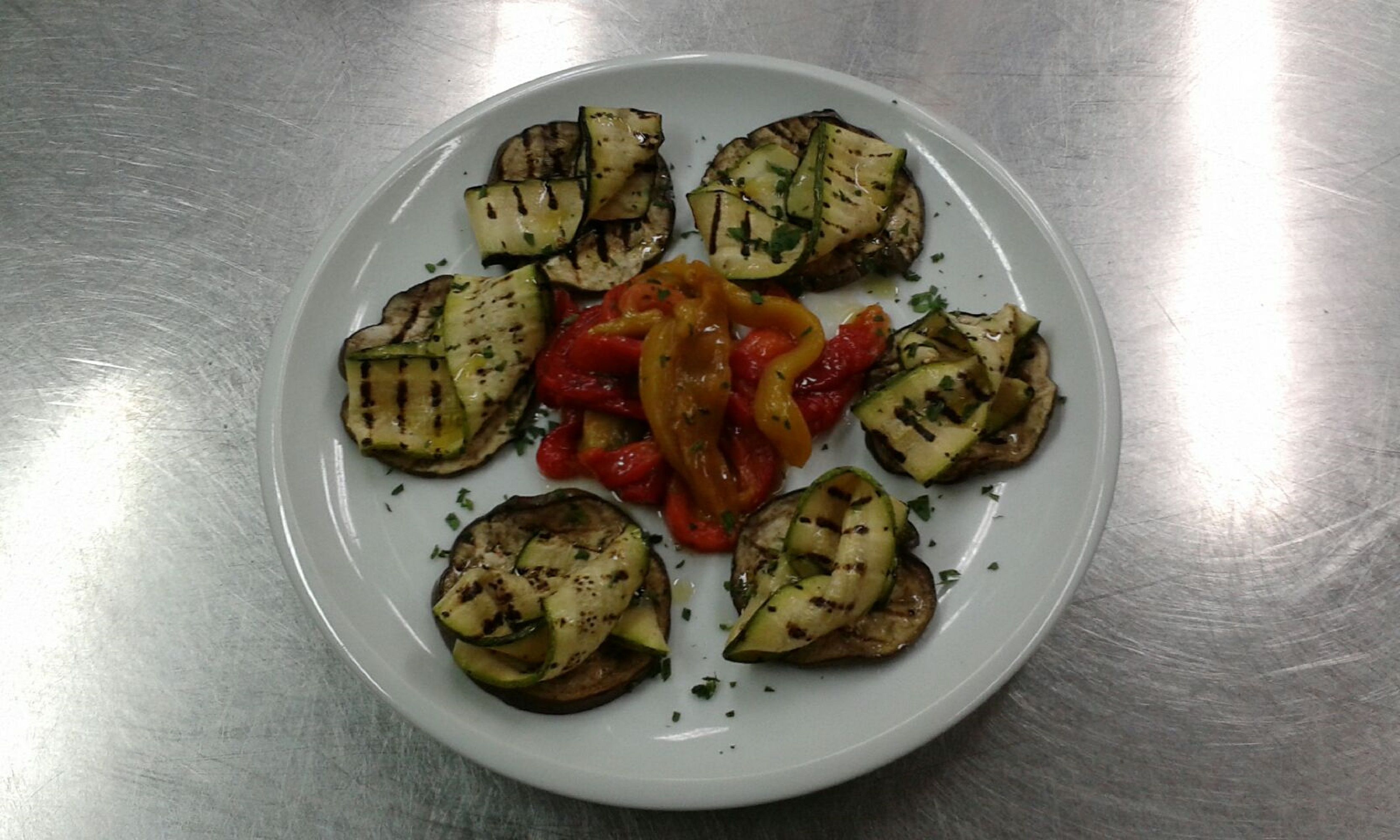 Un plato blanco con verduras a la parrilla y salsa roja.