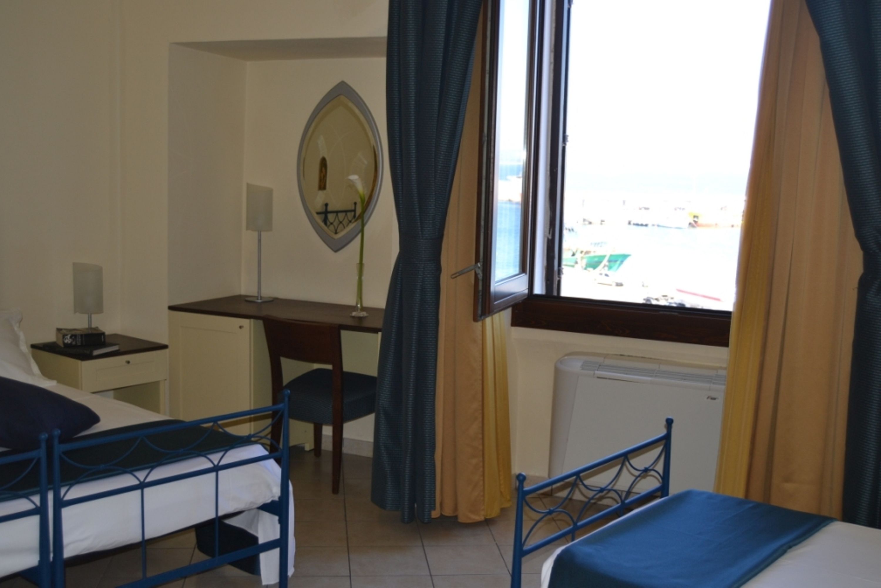 Une chambre d’hôtel avec deux lits, un bureau, un miroir et une fenêtre avec des rideaux.
