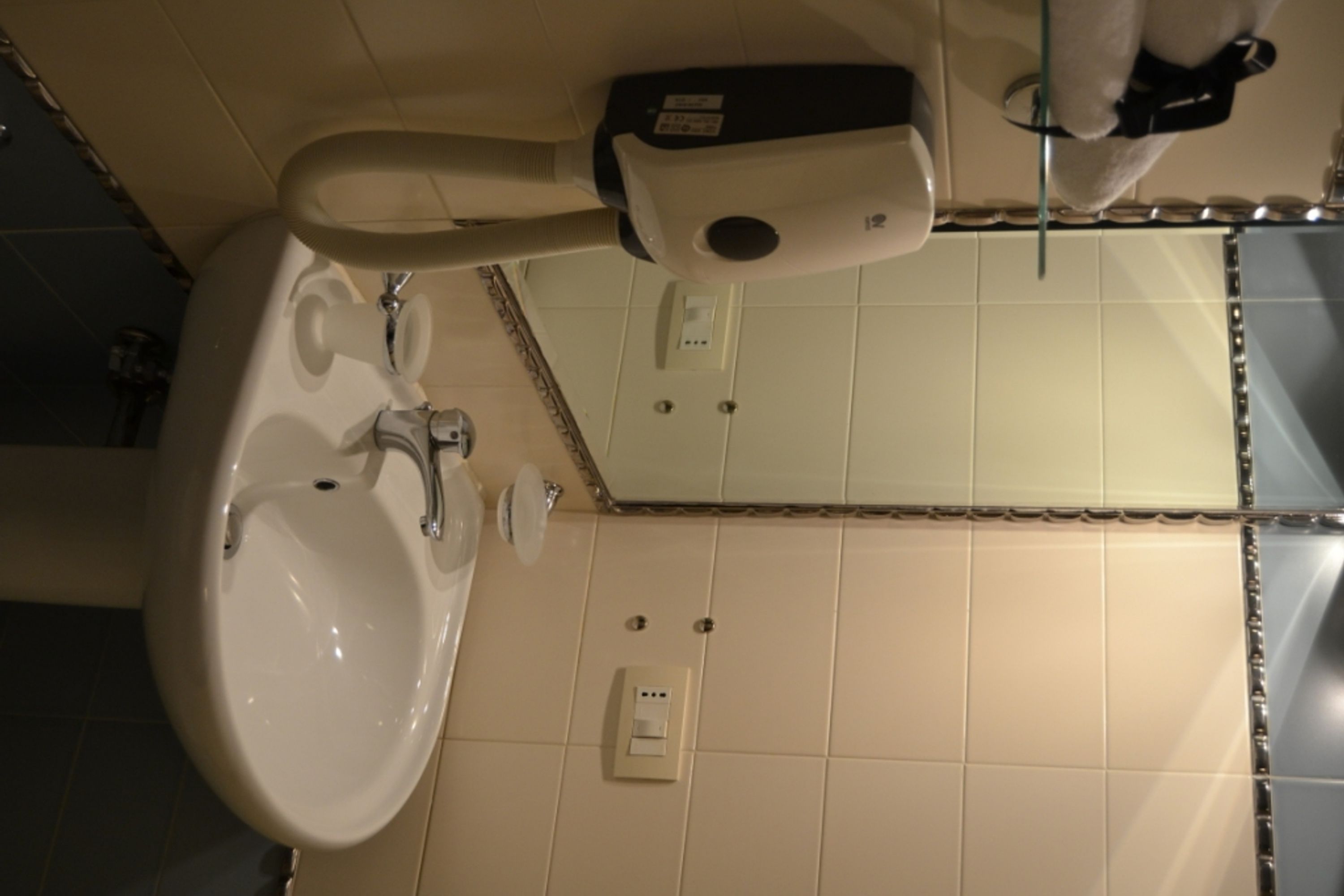 A bathroom with a sink, mirror, and hand dryer.