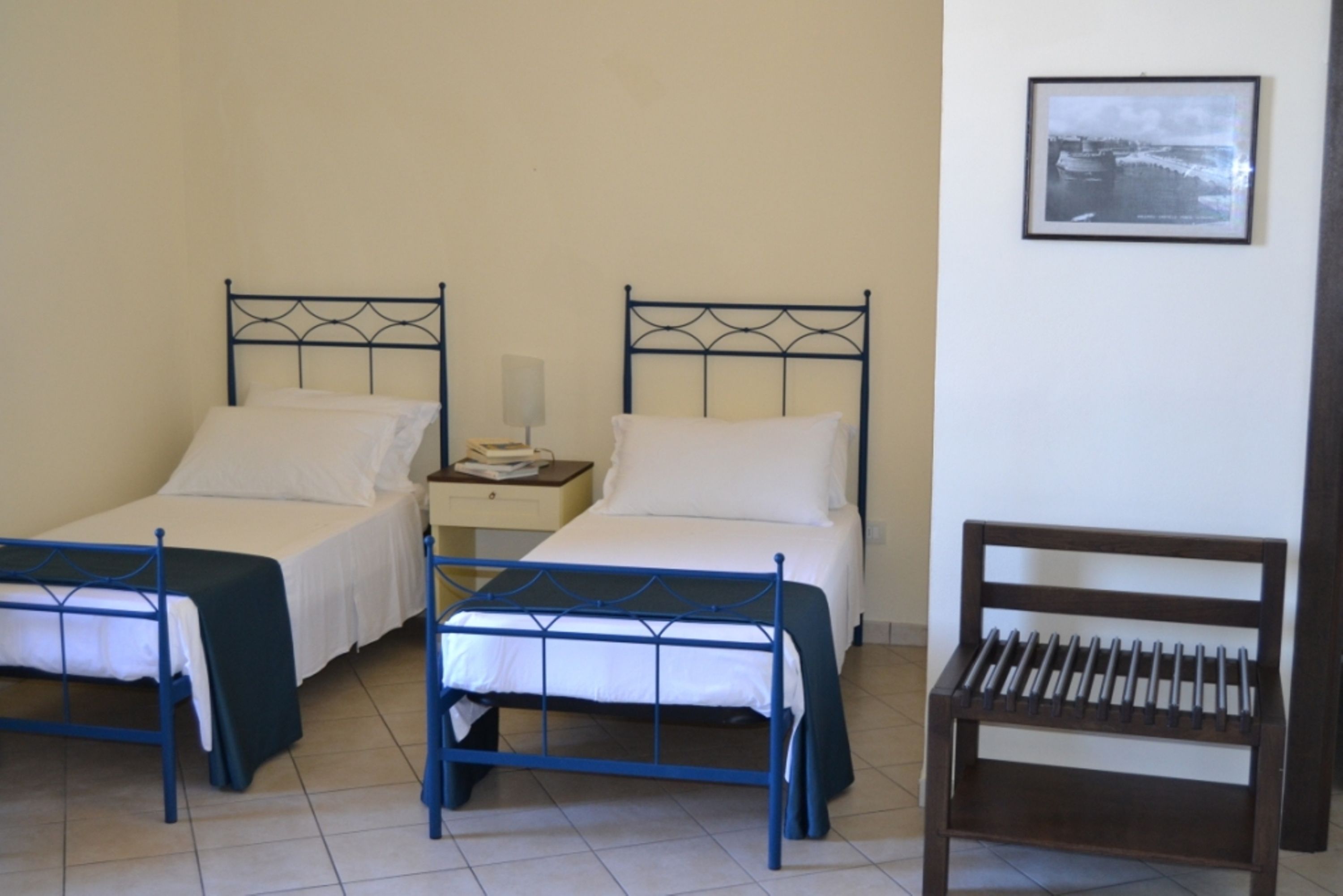 Une chambre avec deux lits, une table de chevet avec une lampe et un banc.