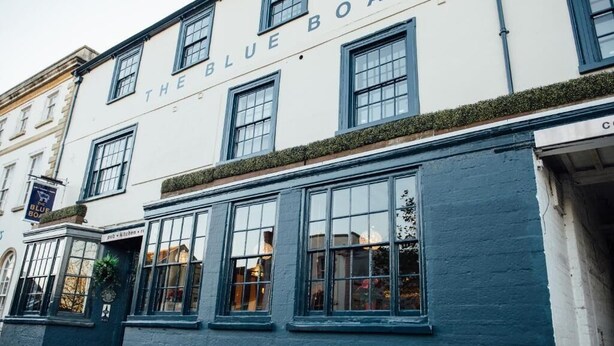 Un edificio con el letrero 'The Blue Board', ventanas amplias y un cartel de pub.
