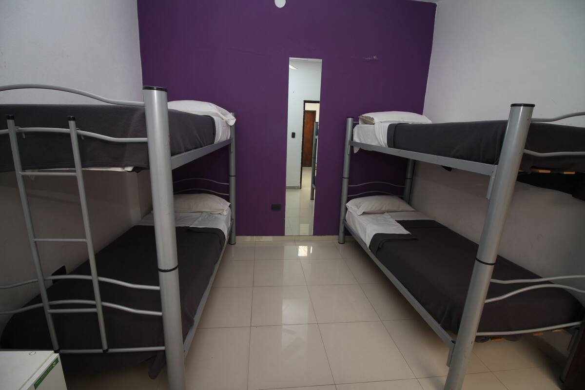 A room with bunk beds, a purple wall, and a door leading to another room.