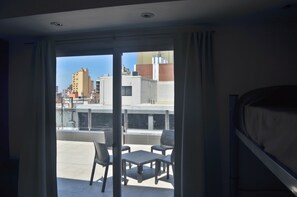 Una habitación con balcón, cama y vistas a edificios.