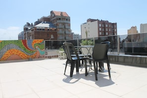 Terraza en la azotea con mobiliario exterior y un mural colorido.