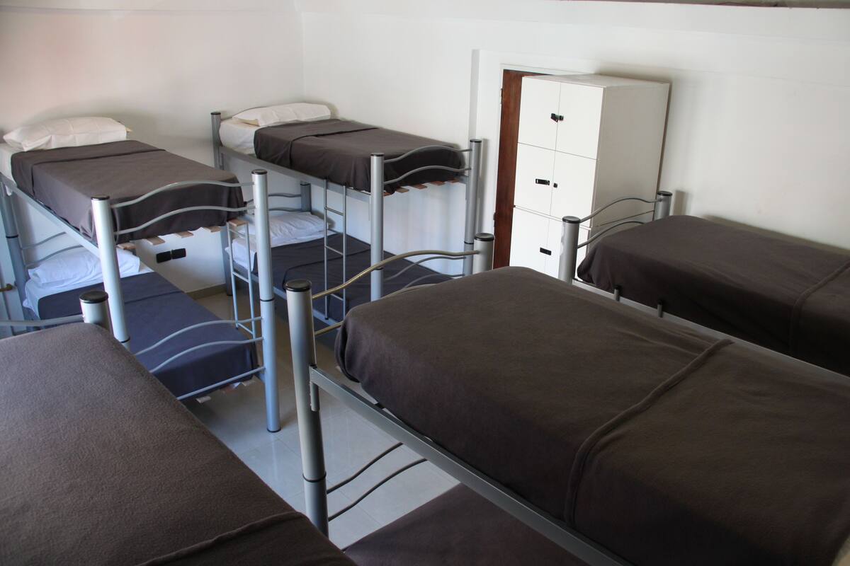A dormitory room with bunk beds, a white cabinet, and a door.