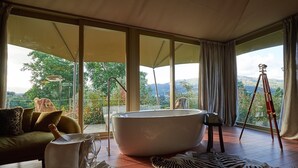 Une salle de bain moderne dotée d’une grande baignoire, d’un télescope et offrant une vue panoramique sur les montagnes et les arbres.