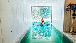 Une petite piscine intérieure où une personne porte un maillot de bain rouge.