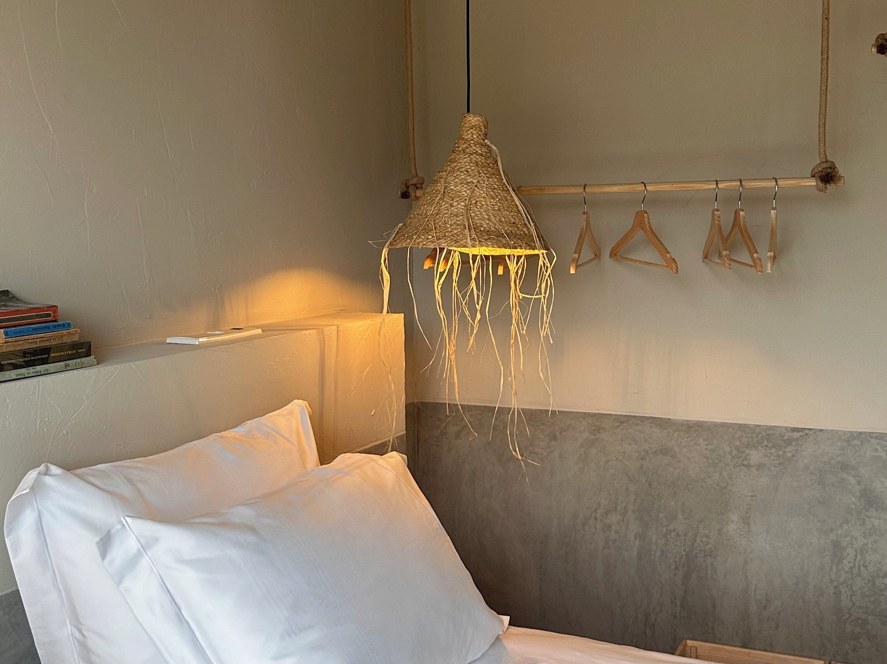 Un dormitorio con cama, lámpara colgante y un perchero de pared.