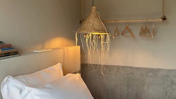 Un dormitorio con cama, lámpara colgante y un perchero de pared.