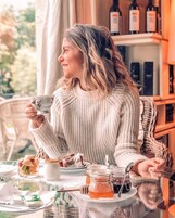 Una persona sentada a una mesa con un vaso de jugo, un tarro de miel y una tetera.