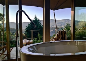 A hot tub on a deck with a view of a mountainous landscape.