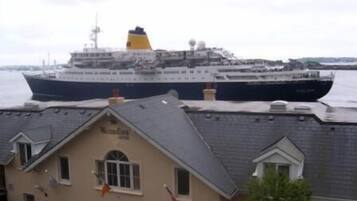 A large cruise ship docked at a port with a building labeled "Waterfront Hotel" in the foreground.